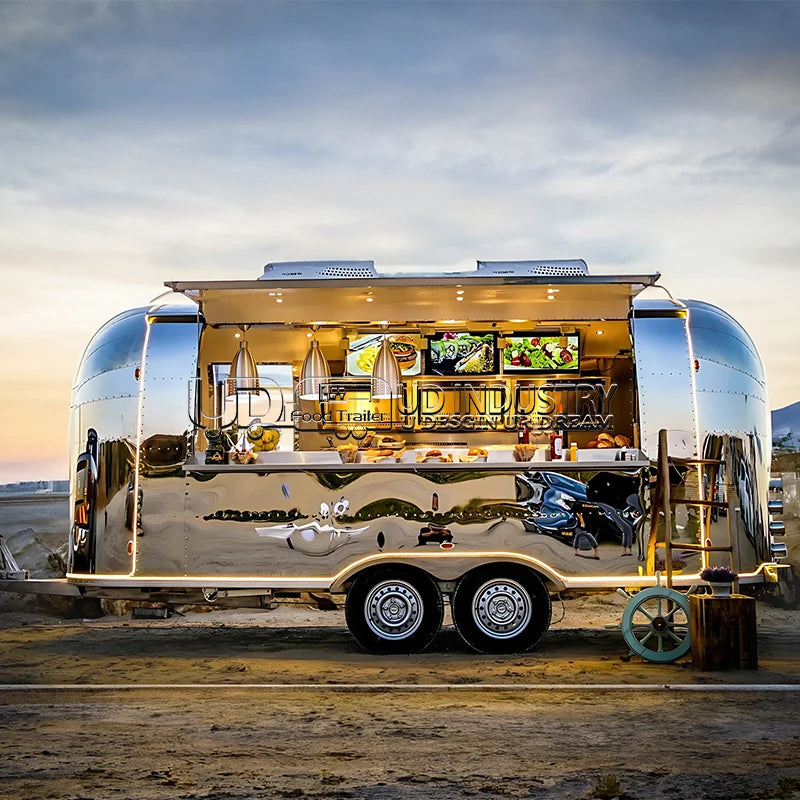 HighPeak Airstream Food Trailer with polished stainless steel exterior and open service window at sunset outdoors