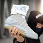 NeoVolt Sneakers in light gray with white strap and speckled sole held by person, showcasing futuristic design and comfort.