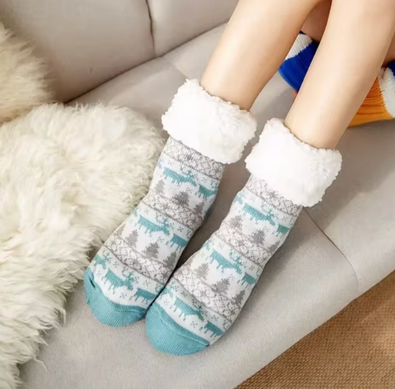 Cozy Christmas socks with nordic reindeer pattern in turquoise and gray, featuring plush white fleece lining on gray couch