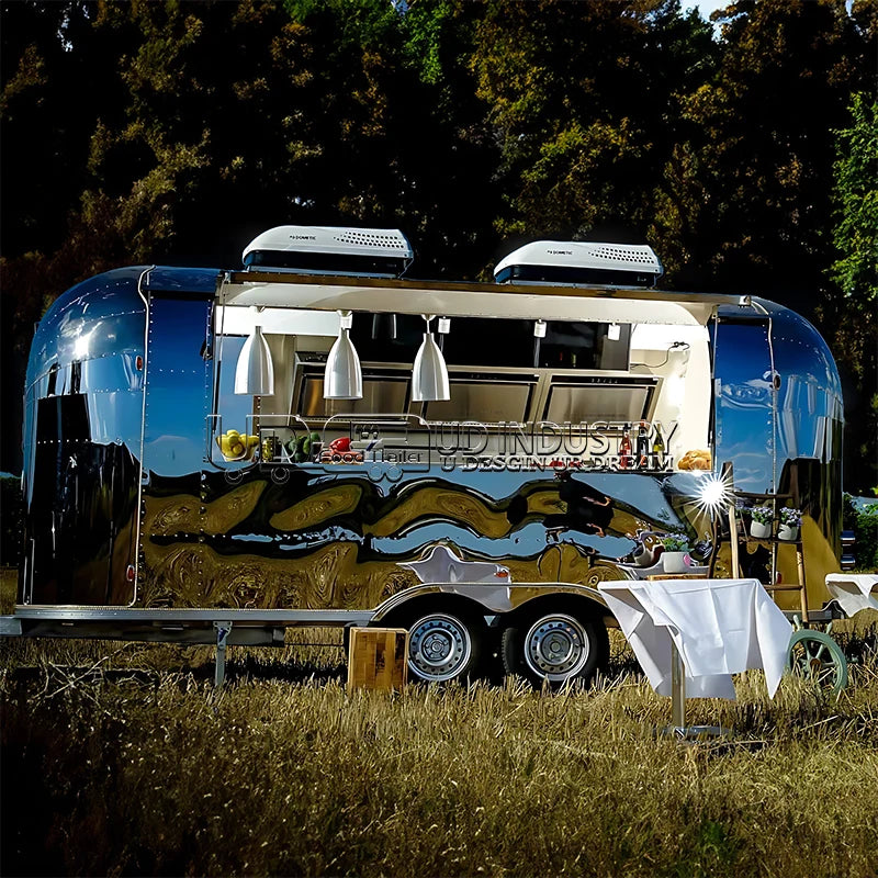 HighPeak Airstream Food Trailer with polished stainless steel exterior and commercial kitchen set outdoors in grassy area