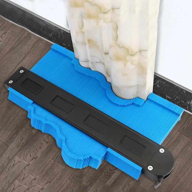 ShapeMaster Contour Gauge in blue and black demonstrating profile measurement against white baseboard on wood floor