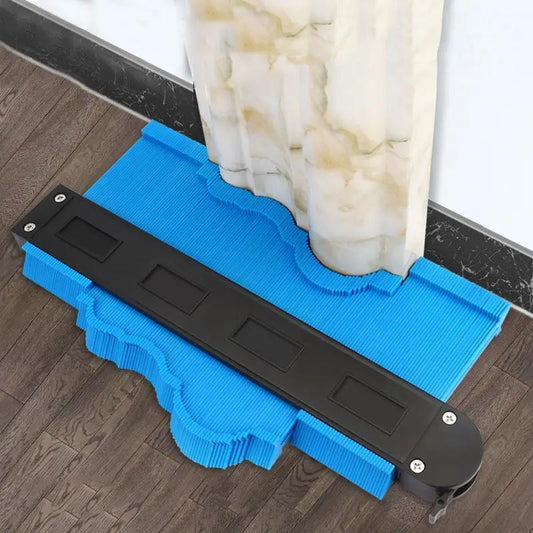 ShapeMaster Contour Gauge in blue and black demonstrating profile measurement against white baseboard on wood floor