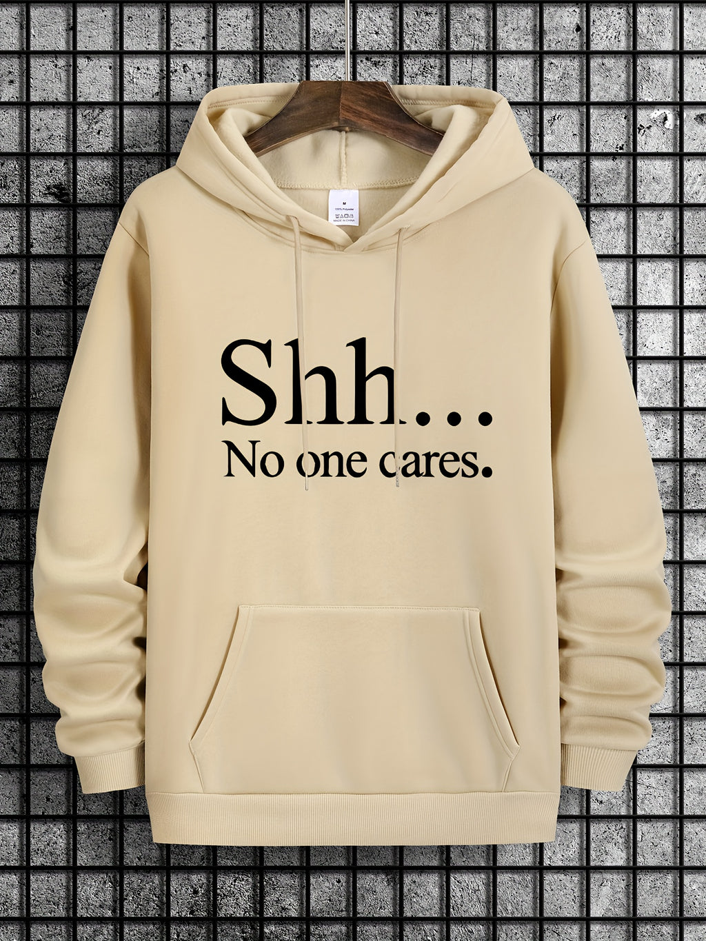 Shh No One Cares hoodie in beige with black text print, front kangaroo pocket and classic pullover style on display