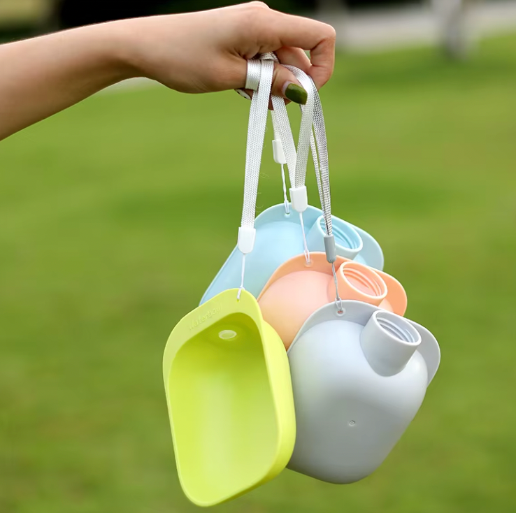 SipPup Cap portable pet water dispensers in pastel colors - blue, peach, yellow, and grey - held outdoors against green grass