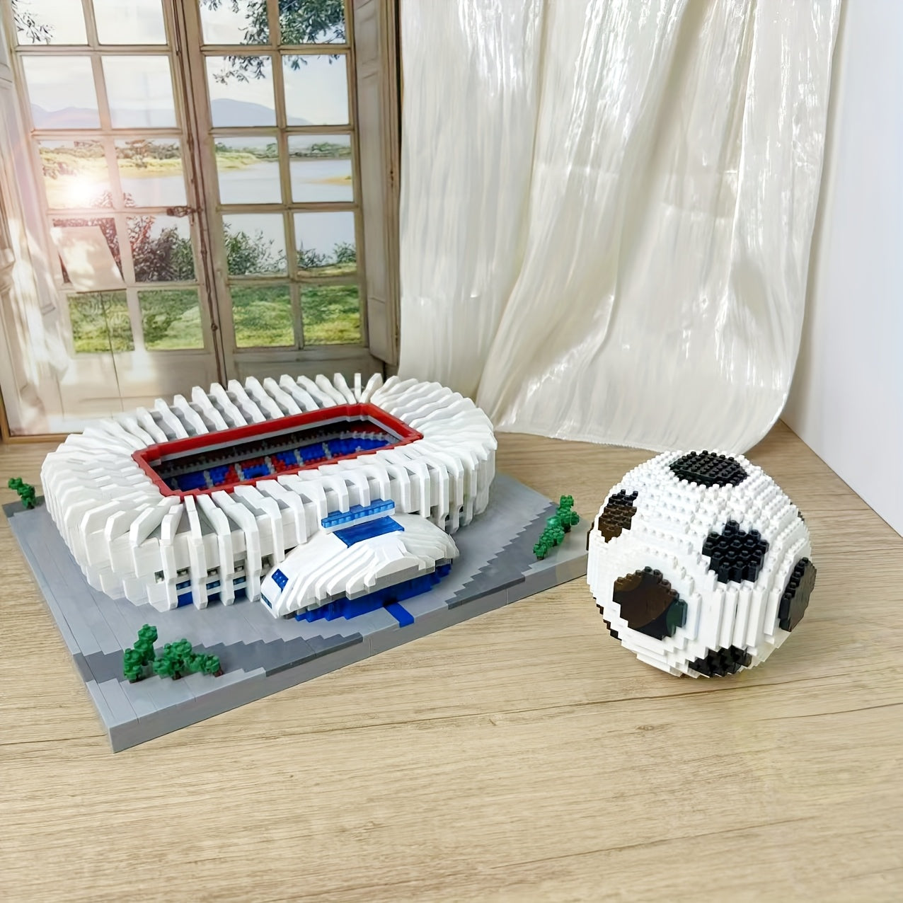 StadiumMaster football stadium building set with detailed white arena model and decorative soccer ball on wooden surface near window