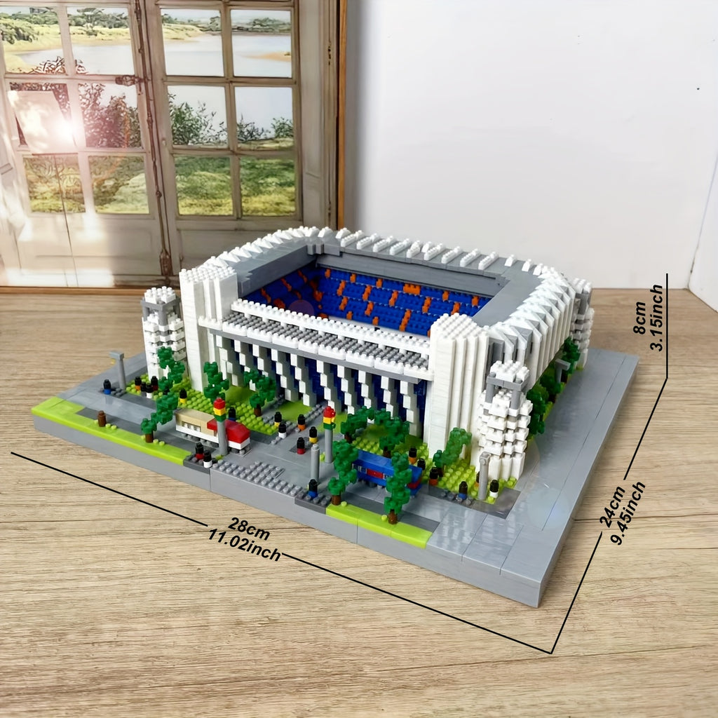 StadiumMaster miniature football stadium building set in white with blue interior and green landscaping on wooden surface