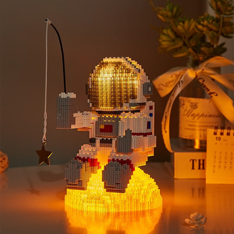 Starlight Voyager illuminated astronaut building brick set with glowing helmet, sitting on lunar surface and star pendant