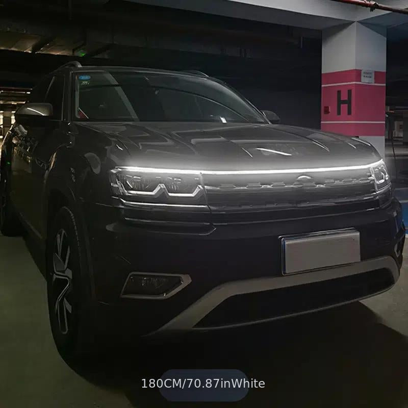 StrikeLine LED hood light strip illuminating front grille of black SUV in dark parking garage with bright white glow