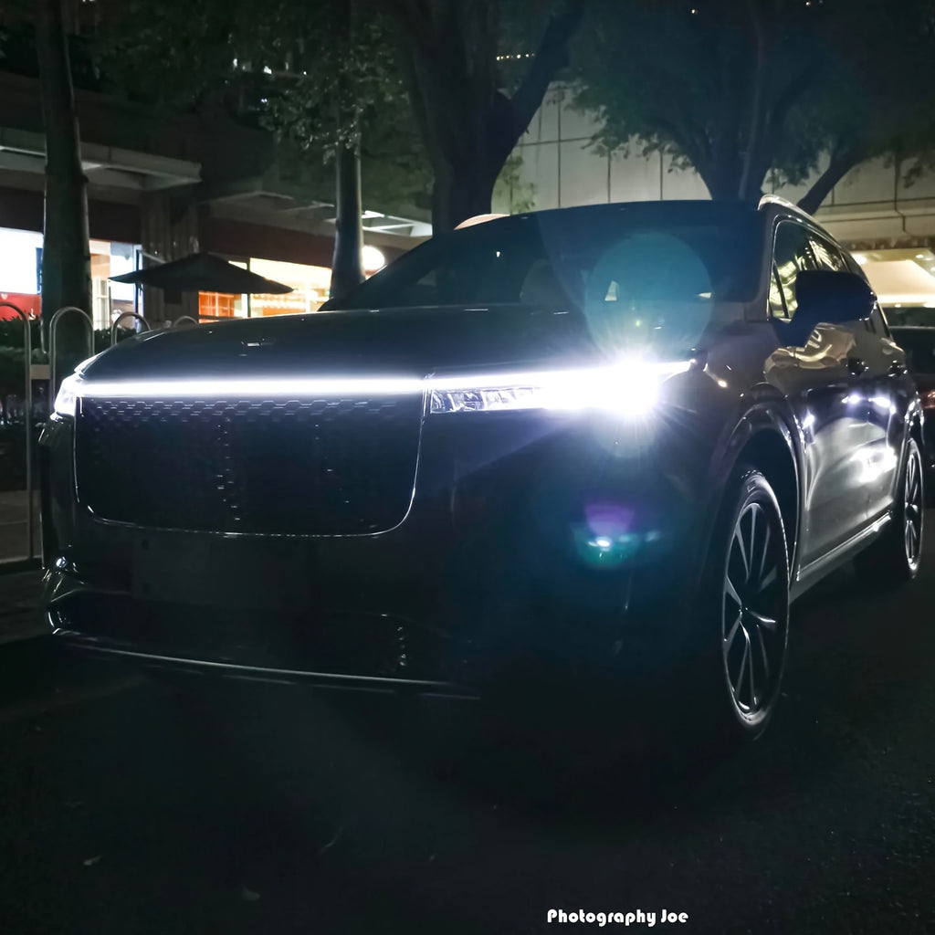StrikeLine LED hood light strip installed on black SUV at night, creating bright white illumination across front grille