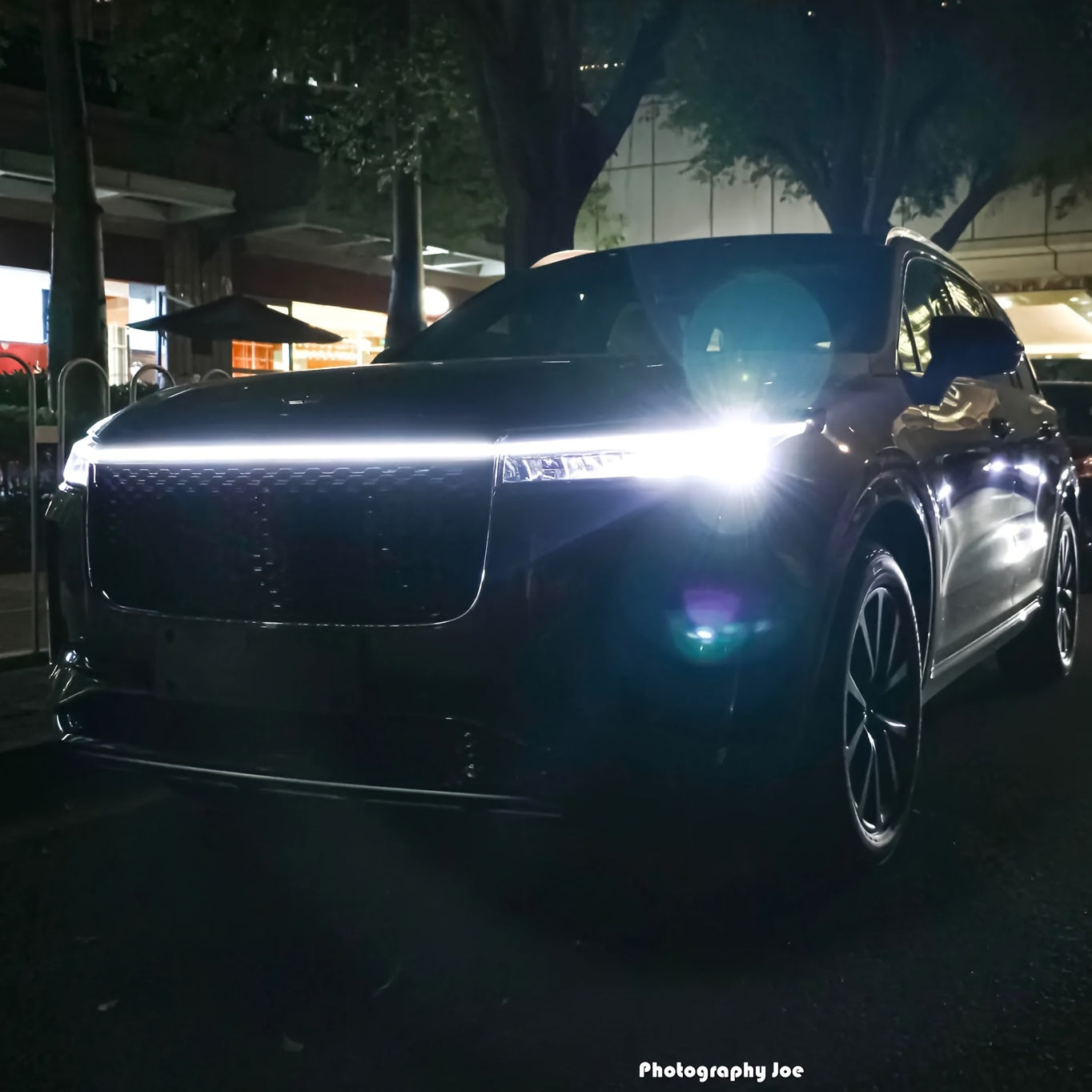 StrikeLine LED hood light strip installed on black SUV at night, creating bright white illumination across front grille