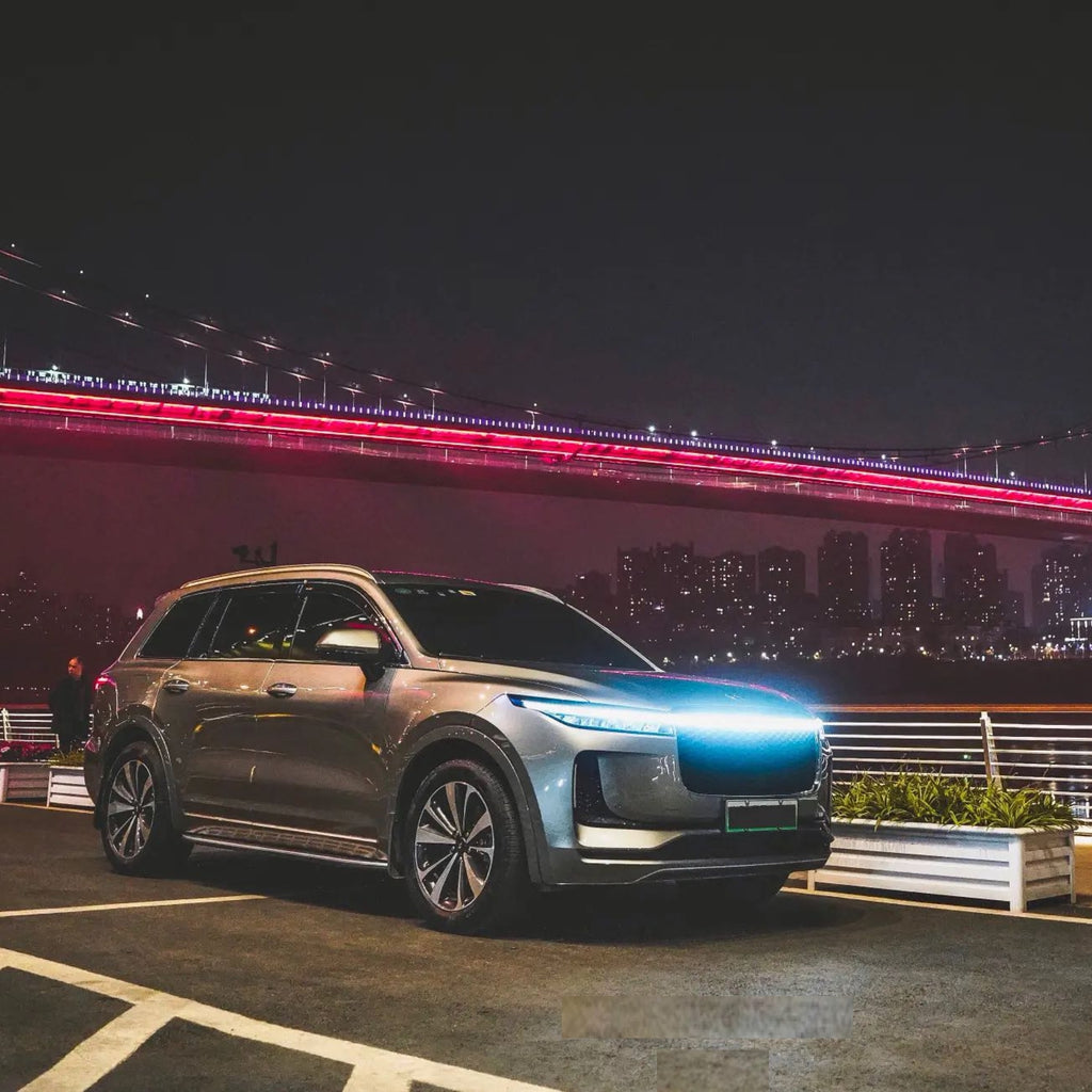 StrikeLine LEDs illuminating SUV hood in blue against nighttime cityscape with red-lit bridge - modern automotive lighting upgrade