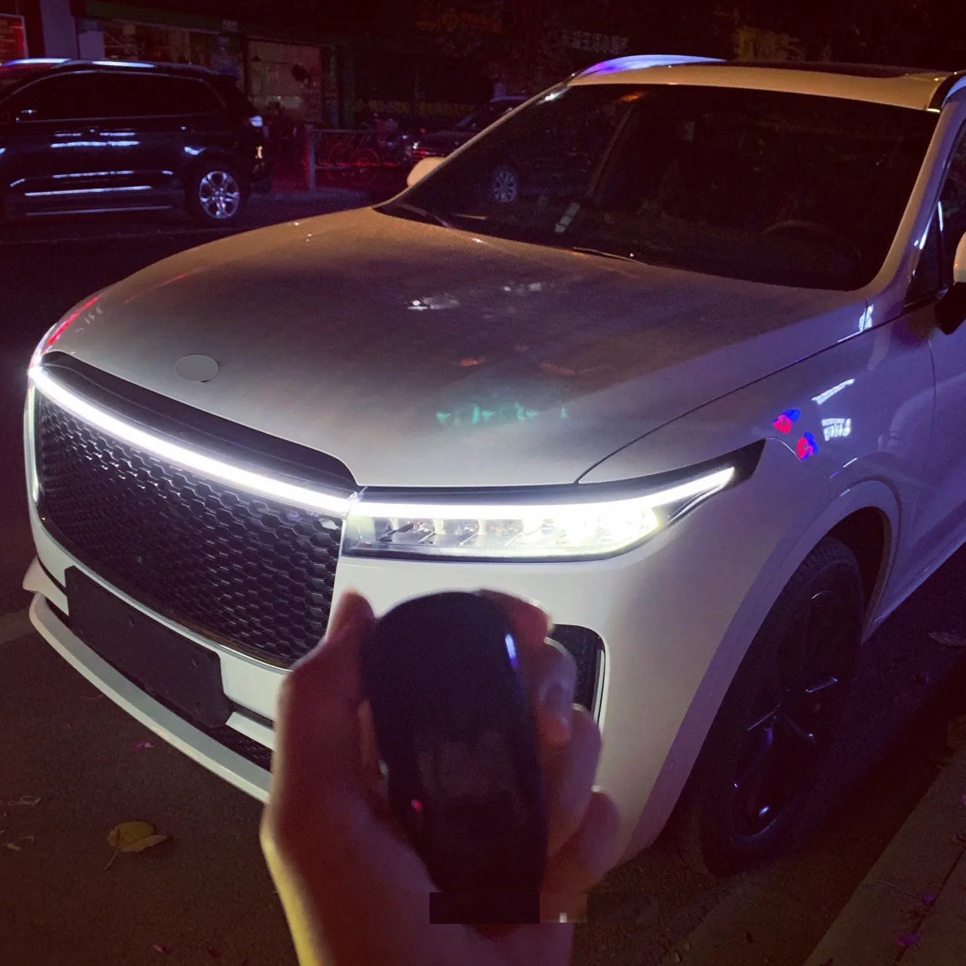 StrikeLine LEDs illuminating white SUV hood with bright continuous LED strip across front grille showing modern lighting upgrade