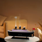 TitanicMist diffuser with LED lights and active steam from smokestacks on white table - ship-shaped aromatherapy display