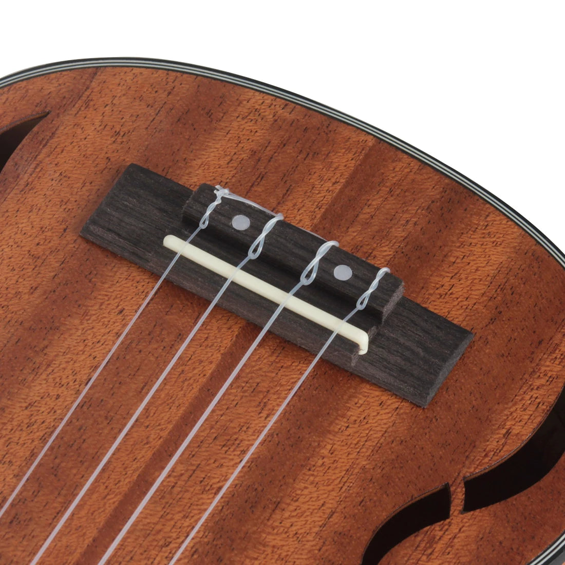 Acoustic Four-String Ukulele bridge close-up with four nylon strings tied over a pale saddle.