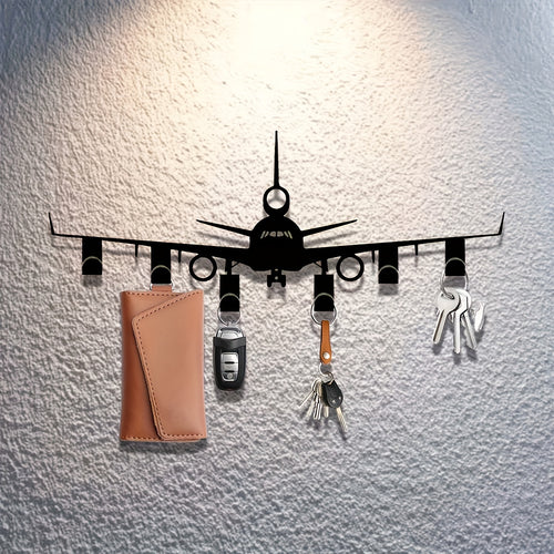 Airplane Key Holder in black metal on a textured white wall, holding keys, a car fob, and a tan pouch.