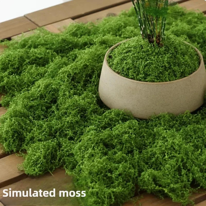 Artificial Decorative Moss arranged around a beige planter on a wooden table, with simulated moss labeling.