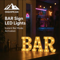 HighPeak BAR Sign LED Lights glowing warm white on a wooden bar counter in a cozy home bar setting