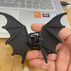 Bat Wing Claw Clip resting in a hand beside a laptop, showing the black wing details.