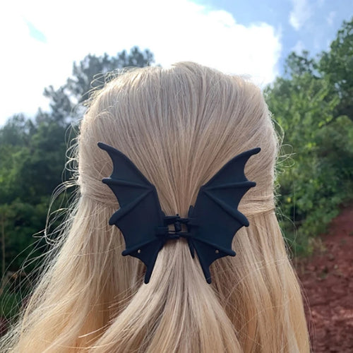 Bat Wing Claw Clip in black securing a half-up hairstyle on blonde hair outdoors.