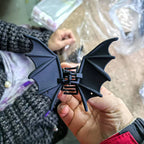Bat Wing Claw Clip held indoors, showing its full black wings and central claw closure.