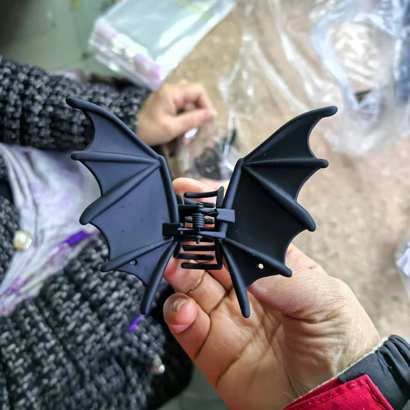 Bat Wing Claw Clip held indoors, showing its full black wings and central claw closure.