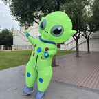 Big-Head Inflatable Alien Costume waving beside a tree-lined walkway, with blue collar and foot coverings.