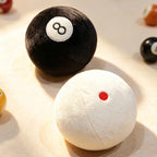 Billiard Ball Plush Set black 8 ball and white cue ball displayed in warm sunlight.