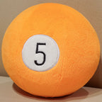 Billiard Ball Plush Set orange number 5 ball resting on a beige seat.