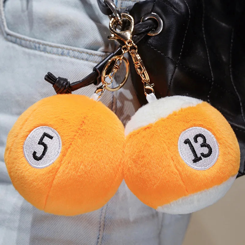 Billiard Ball Plush Set orange number 5 and striped number 13 pendant charms clipped to a black bag.