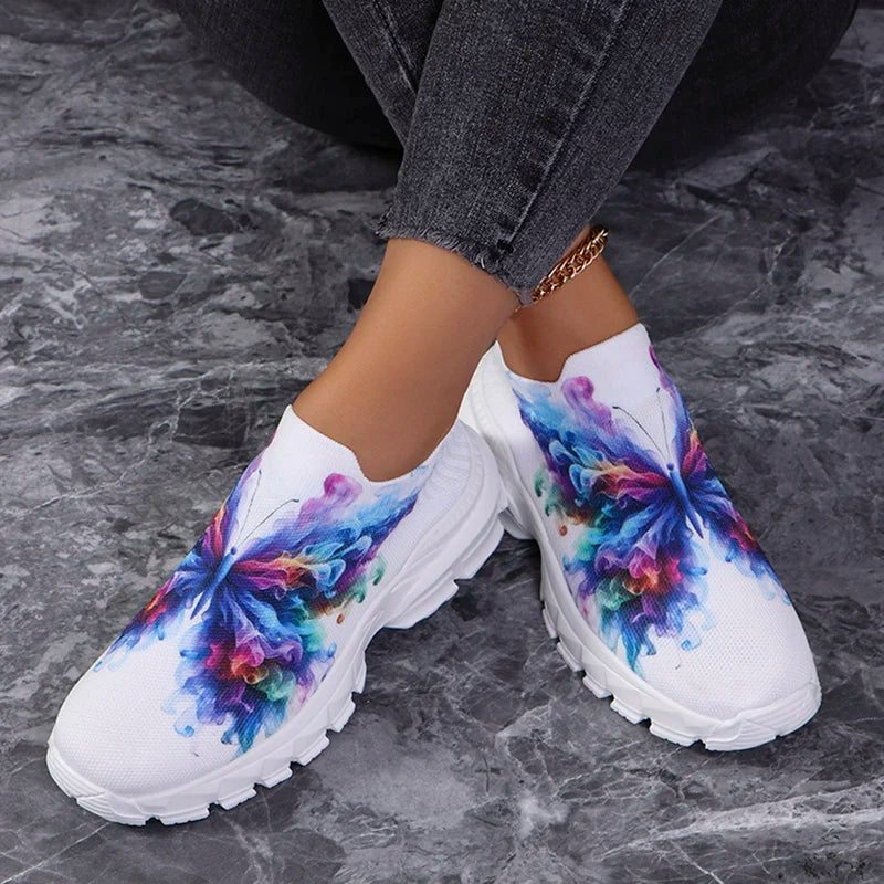 Butterfly Knit Shoes Colorful Butterfly shoes worn with crossed ankles on a gray floor, showing both printed uppers.
