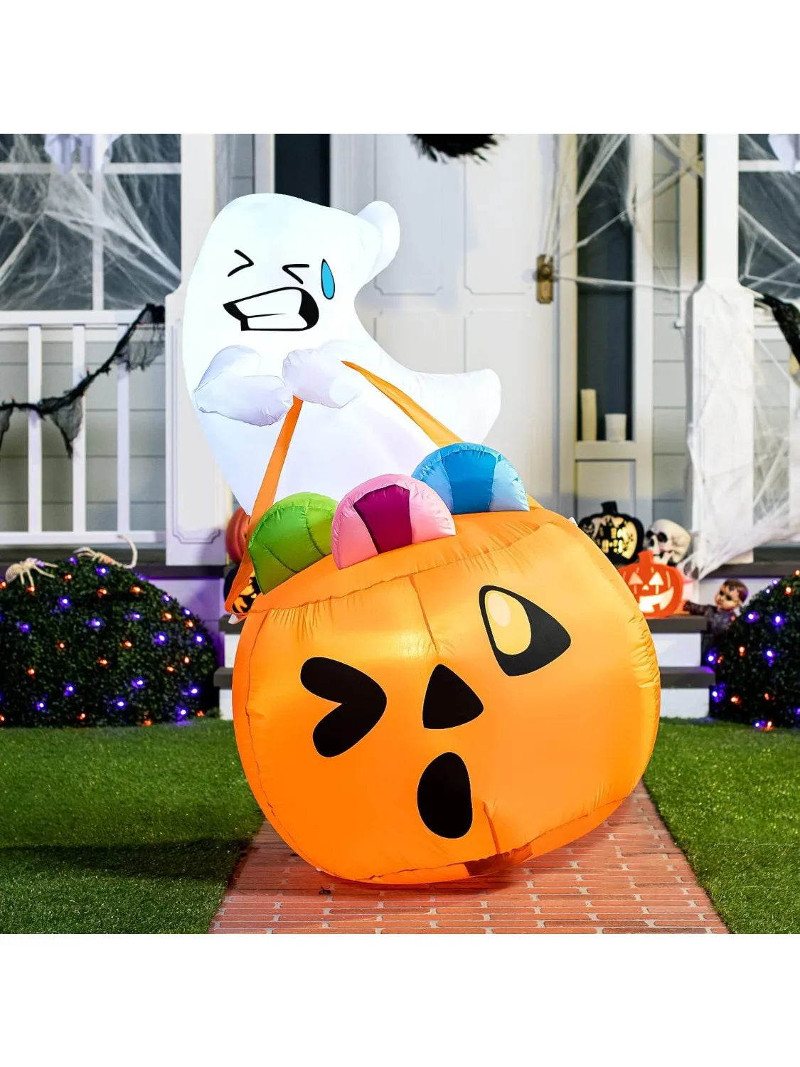 Candy-Carrying Ghost Inflatable holding a pumpkin candy bag on a brick path in a portrait porch scene.