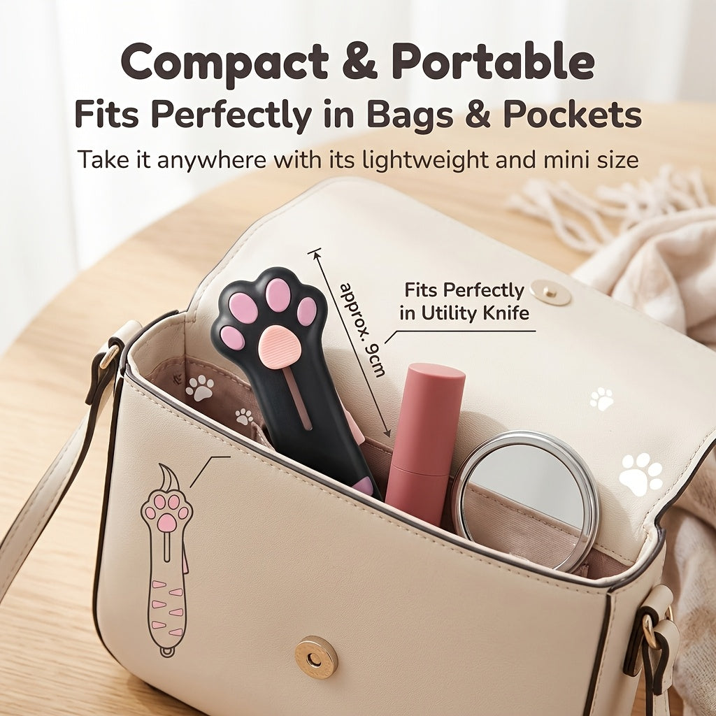 Cat Paw Box Cutter with blade retracted, shown inside a handbag beside personal accessories.