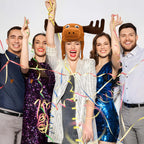 Christmas Moose Hat worn by a smiling party guest surrounded by friends and colorful streamers.