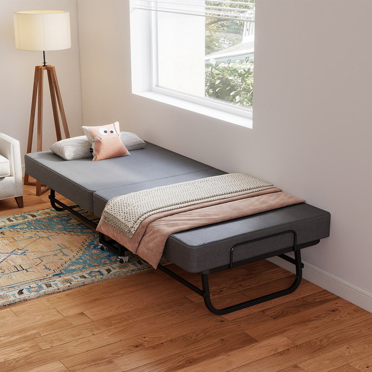 Compact Foldaway Guest Bed positioned under a bedroom window with pillows and a folded blanket.
