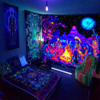 Cosmic Bonfire UV Tapestry hung beside a bed in a blue-lit room with other patterned wall hangings.
