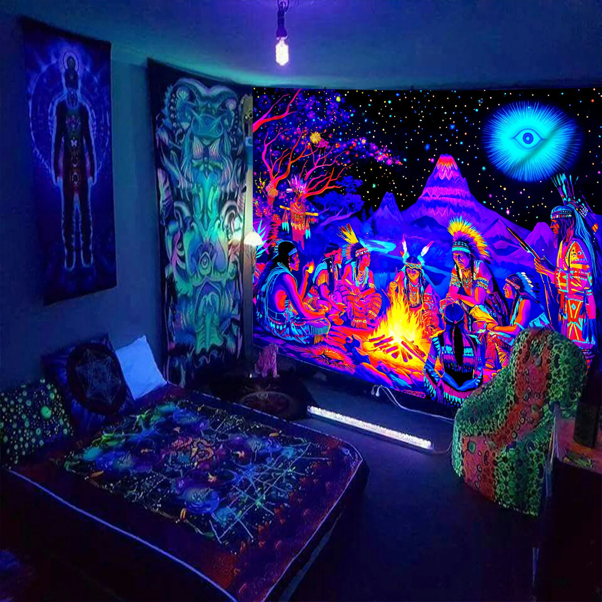 Cosmic Bonfire UV Tapestry hung beside a bed in a blue-lit room with other patterned wall hangings.