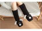 Cozy Dog Ear Socks in black worn by a seated person, with both white puppy faces visible