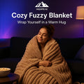 HighPeak Cozy Fuzzy Blanket in warm beige wrapped around a woman on a dark sofa in cozy ambient lighting