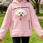Cozy Pet Carrier Hoodie in pink showing the round pet opening and front pockets in a blossoming park