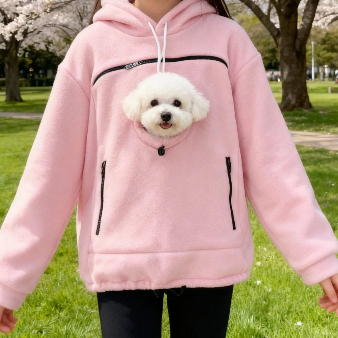 Cozy Pet Carrier Hoodie in pink showing the round pet opening and front pockets in a blossoming park