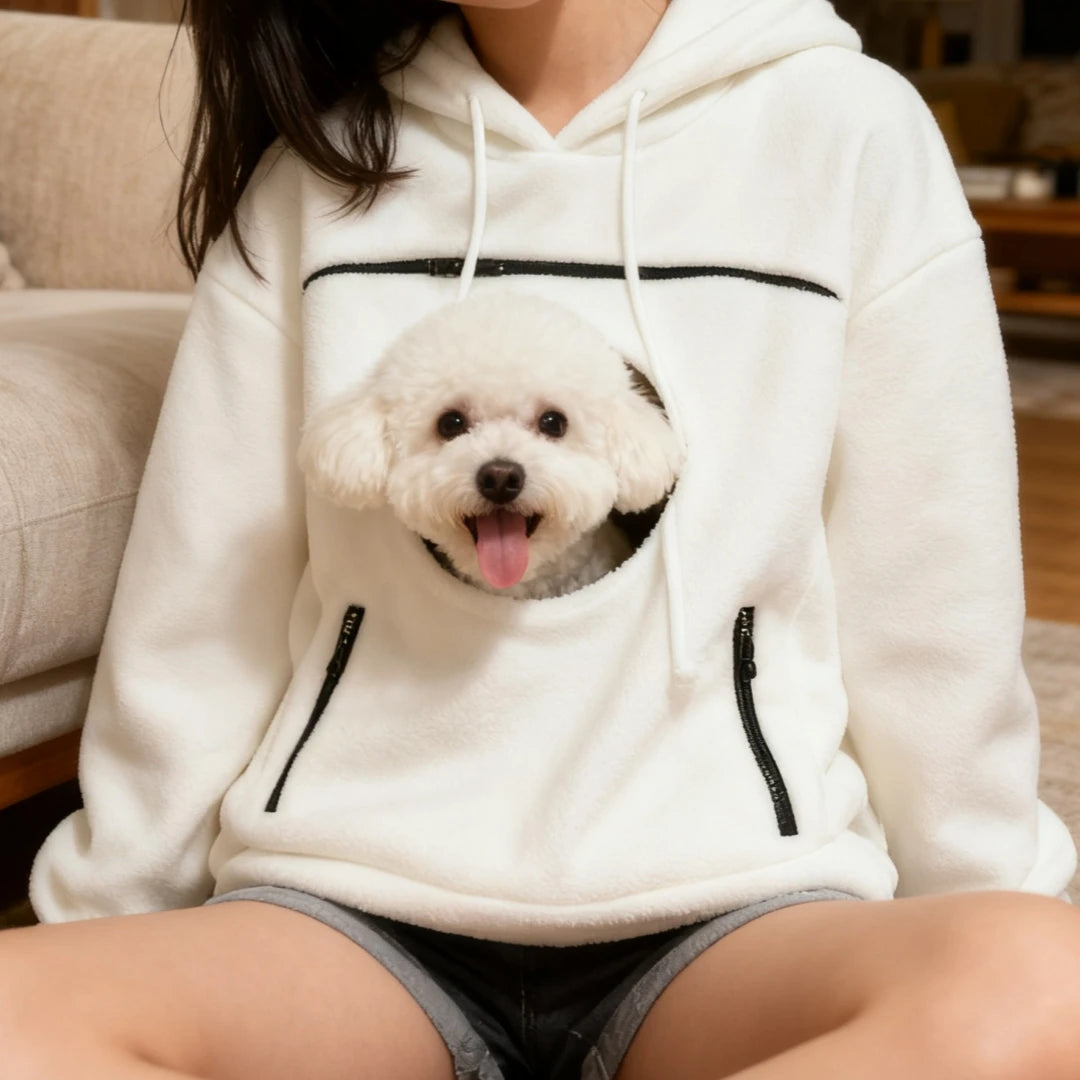 Cozy Pet Carrier Hoodie in white worn while seated indoors with a fluffy dog in the front pouch