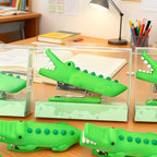 Crocodile Mini Staplers shown in clear display boxes with additional green staplers in front