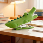 Crocodile Mini Stapler side view showing its green body and metal mechanism beside notebooks