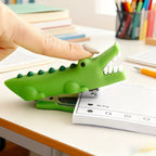 Crocodile Mini Stapler being pressed by a finger to staple papers on a bright desk