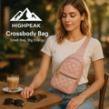 HighPeak Crossbody Bag in pink quilted finish worn by woman sitting at cafe table with coffee and phone nearby