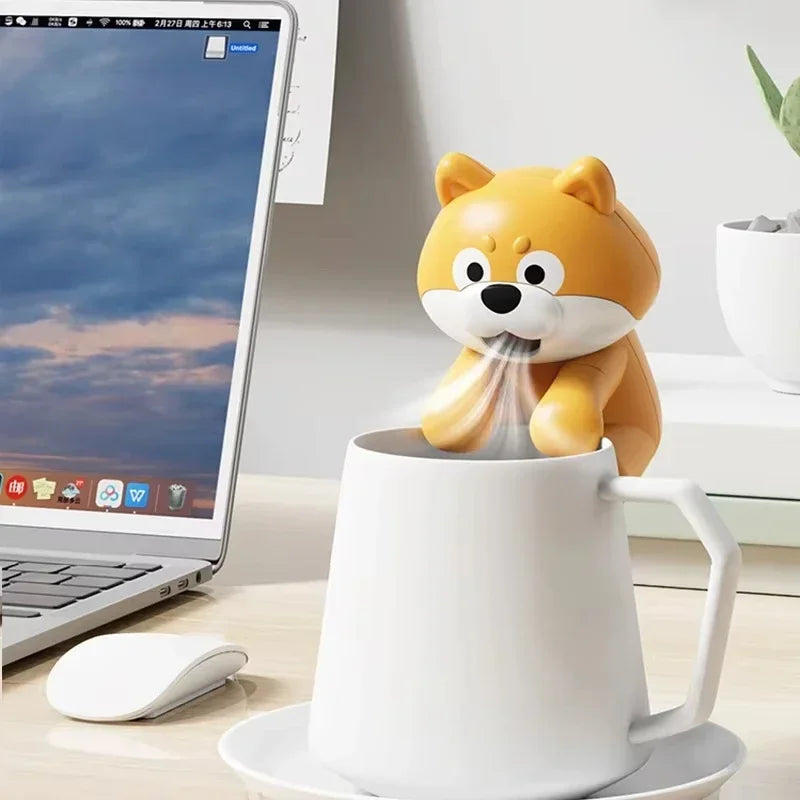Cute Food Cooling Fan resting on a white mug beside a laptop, with airflow illustrated from its mouth