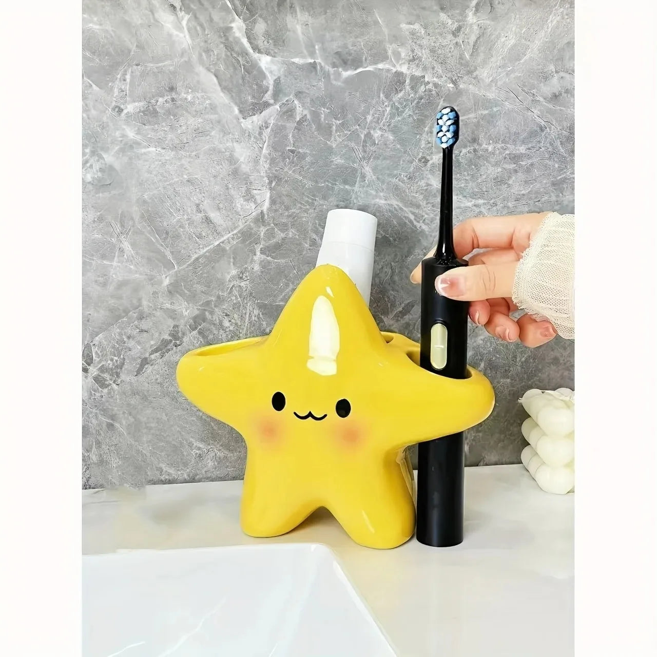 Cute Star Toothbrush Holder with a hand placing a black electric toothbrush into the side opening