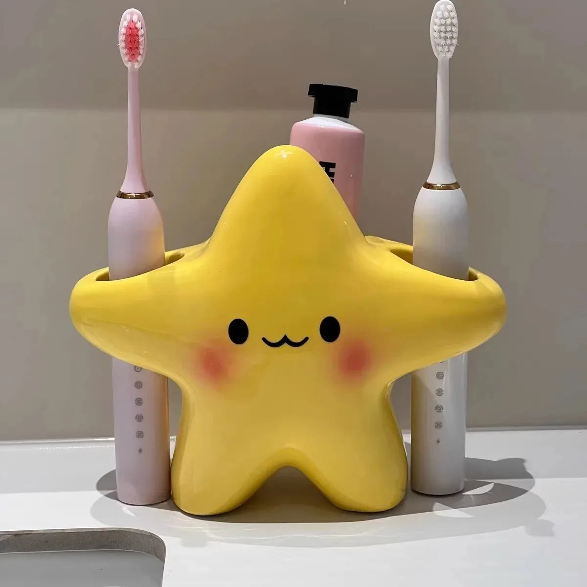 Cute Star Toothbrush Holder organizing two electric toothbrushes and a toothpaste bottle on a bathroom counter
