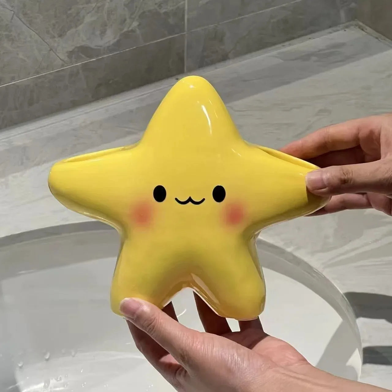 Cute Star Toothbrush Holder shown empty by hand above a bathroom sink, revealing its yellow star shape