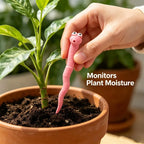 Cute Worm Plant Ornaments: a hand placing a pink decorative worm in soil beside a leafy plant in a terracotta pot.